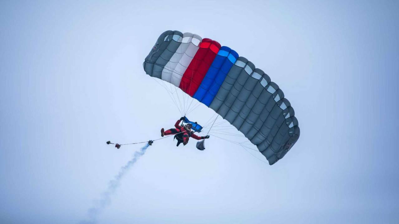 WHA parachute demonstration jumper carrying a flag with smoke during a display